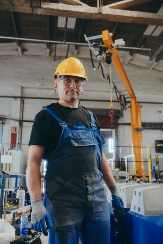 Moll Rail Mitarbeiter steht neben Flieißband mit Blick in die Kamera © Max Freiburger Moll Rail Mitarbeiter steht neben Flieißband mit Blick in die Kamera © Max Freiburger